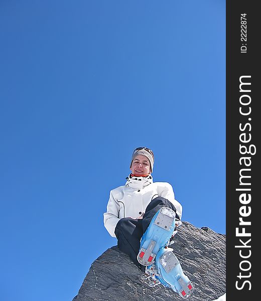 Woman in mountain with skiwears on a rock in the medium of snow. Woman in mountain with skiwears on a rock in the medium of snow