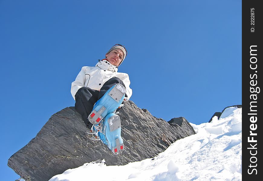 Woman in mountain with skiwears on a rock in the medium of snow. Woman in mountain with skiwears on a rock in the medium of snow