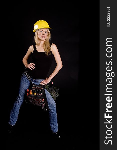 blond female construction worker with hard hat and tool pouch on black background. blond female construction worker with hard hat and tool pouch on black background