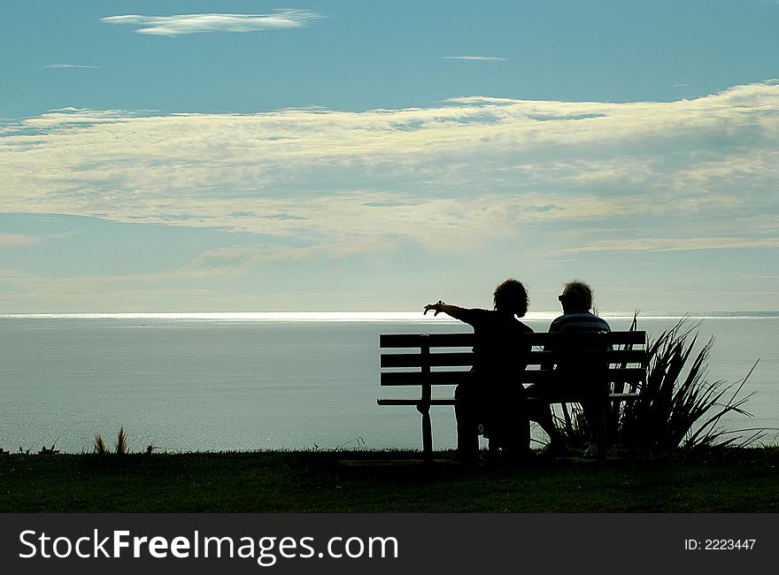 A couple seated looking across ocean. A couple seated looking across ocean