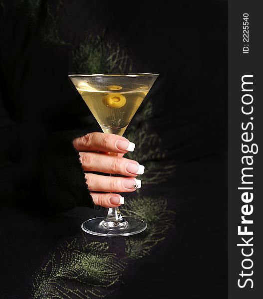 The image of a glass from martinis in a female hand on a black background. The image of a glass from martinis in a female hand on a black background