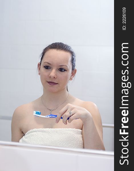 A young woman cleaning her teeth in bathroom mirror. A young woman cleaning her teeth in bathroom mirror