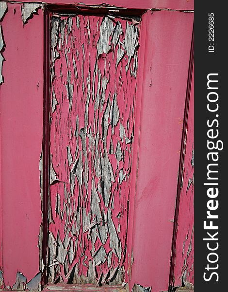 An old wooden door with peeling faded red paint. An old wooden door with peeling faded red paint