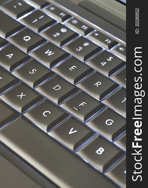 A closeup of a backlit computer keyboard with shallow depth of field and something of an optical illusion due to angle of image capture.