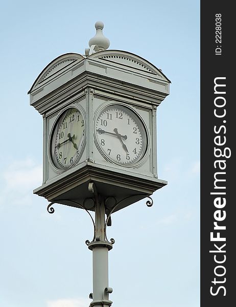 Street clock in Budapest at quarter to five against blue sky.