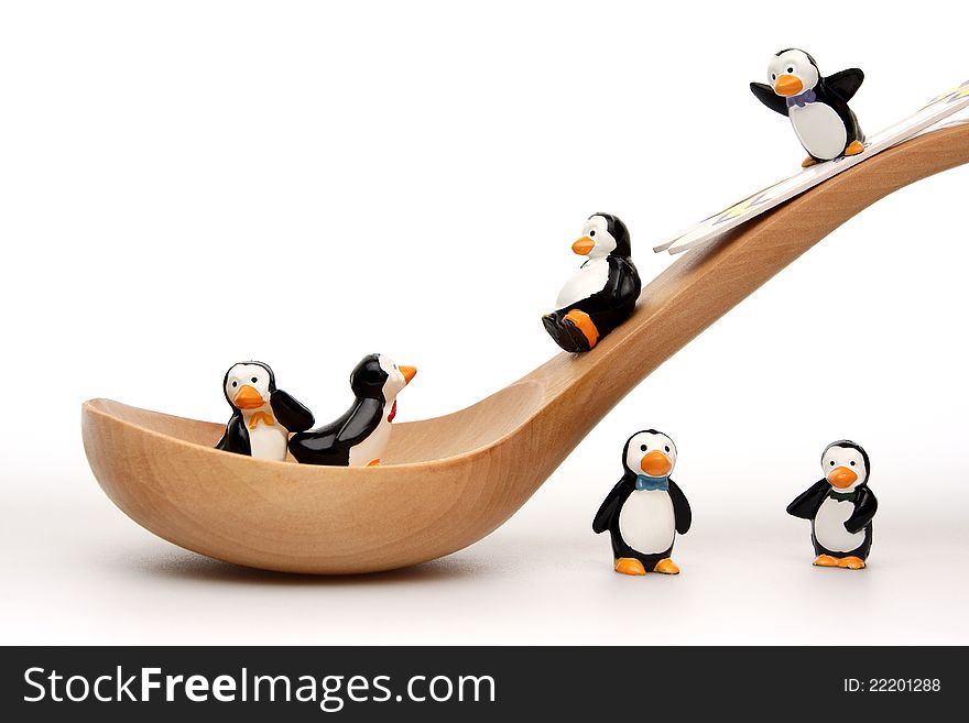 Happy penguins playing on a wooden spoon on white background