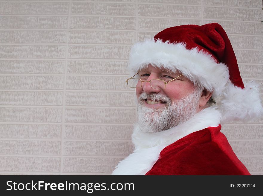 Smiling Santa in front of a white brick wall. Smiling Santa in front of a white brick wall.