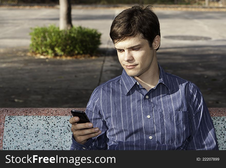 A young man in the park with mobile phone. A young man in the park with mobile phone