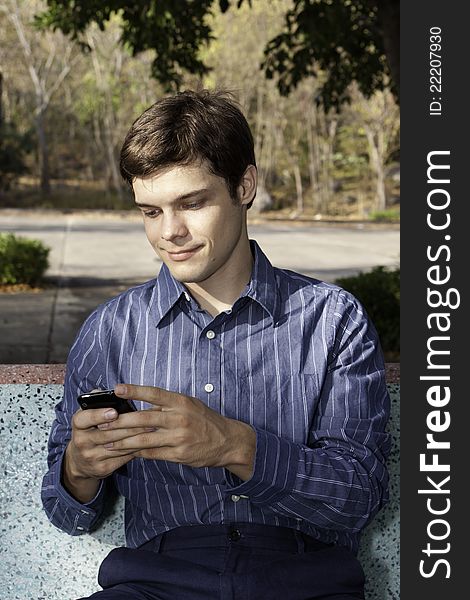 A young man in the park with mobile phone. A young man in the park with mobile phone