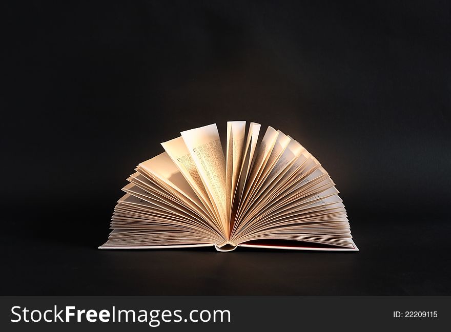 Open book under beam of light on dark background. Open book under beam of light on dark background