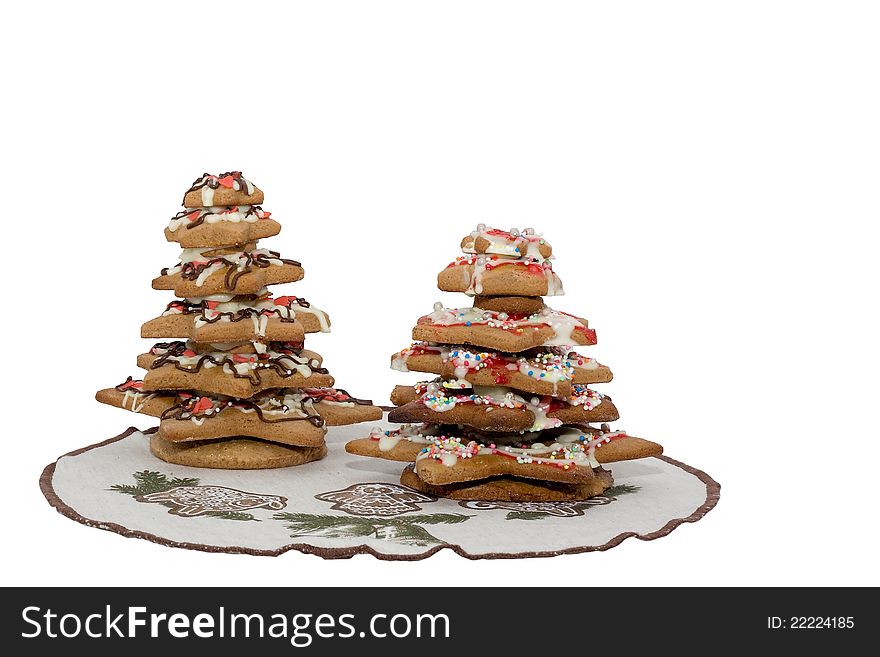 Two colorful gingerbread Christmas trees with white icing on christmas place mats.