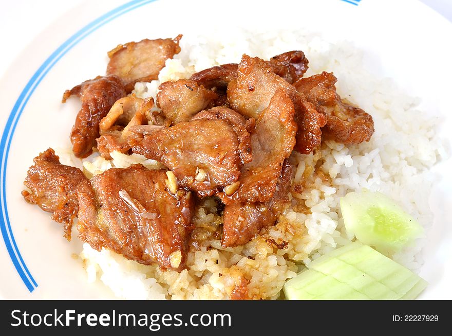 Fried pork with garlic and pepper on rice , served with fresh cucumber. Fried pork with garlic and pepper on rice , served with fresh cucumber