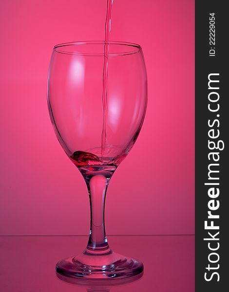 Pouring wine into a glass on a pink background. Pouring wine into a glass on a pink background.