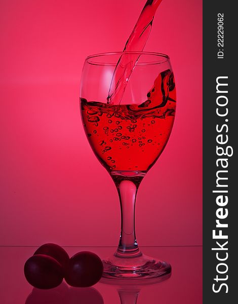 Red wine in glass, on a pink background. Red wine in glass, on a pink background.