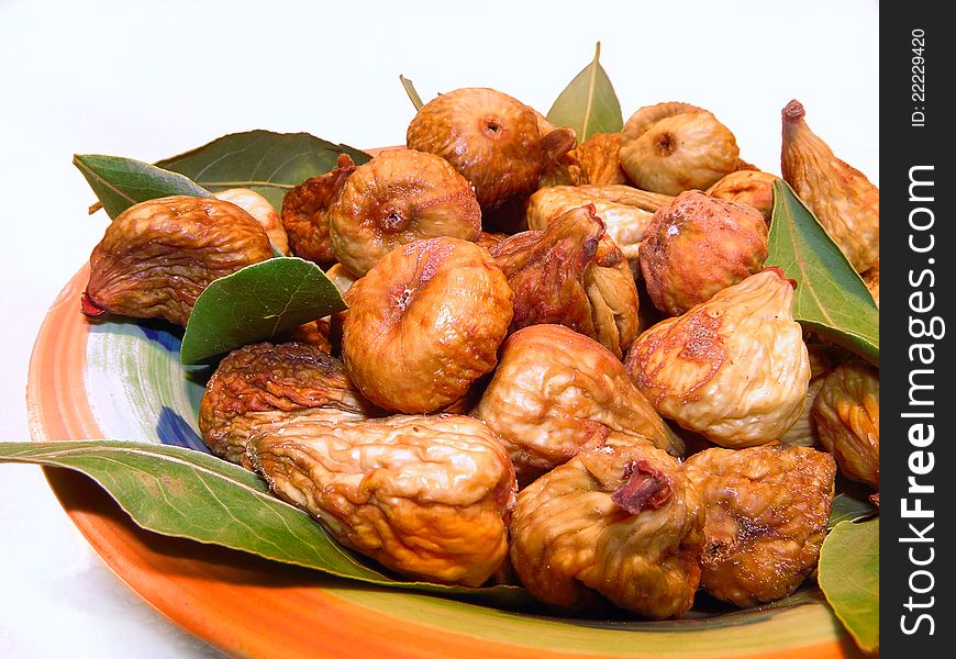 Dried figs with dry laurel leaves in a bowl.