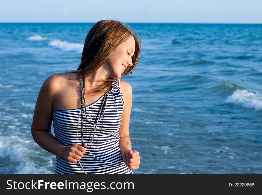 Young pretty girl closed eyes and smiling with the sea as a background. Young pretty girl closed eyes and smiling with the sea as a background