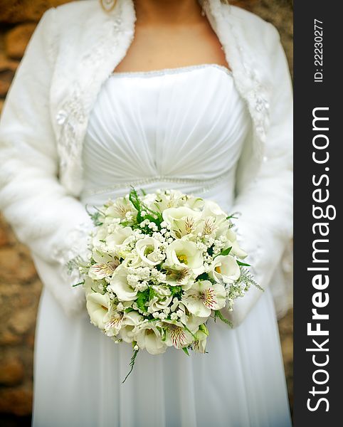 Unrecognizable bride is holding a wedding bouquet, focus is on white flowers. Unrecognizable bride is holding a wedding bouquet, focus is on white flowers