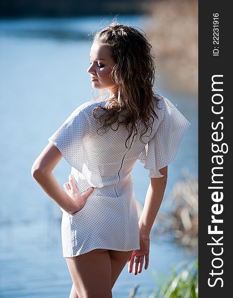 Portrait of sexy young woman in a mini dress posing against the backdrop of water somewhere in the nature. Portrait of sexy young woman in a mini dress posing against the backdrop of water somewhere in the nature