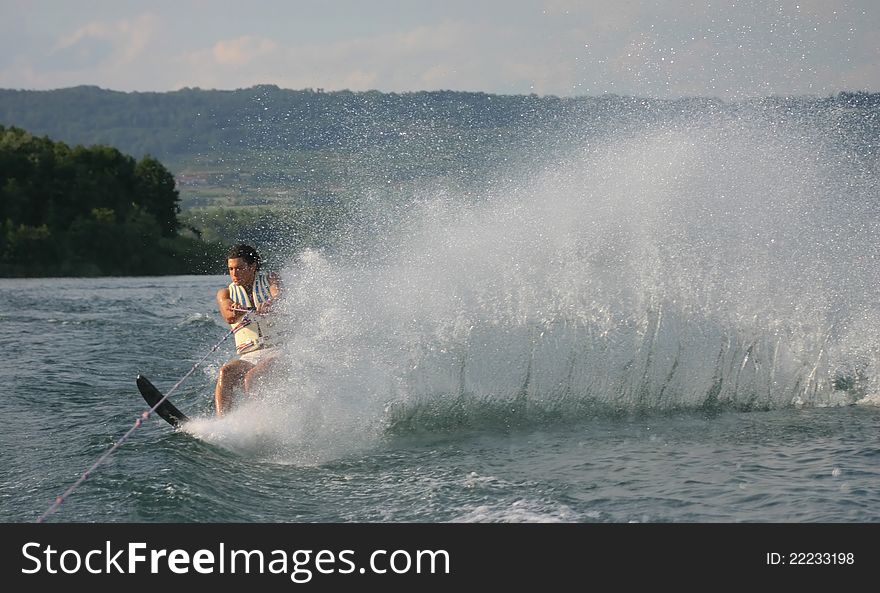 Young man is skiing with a mono and raising a wall of water. Young man is skiing with a mono and raising a wall of water