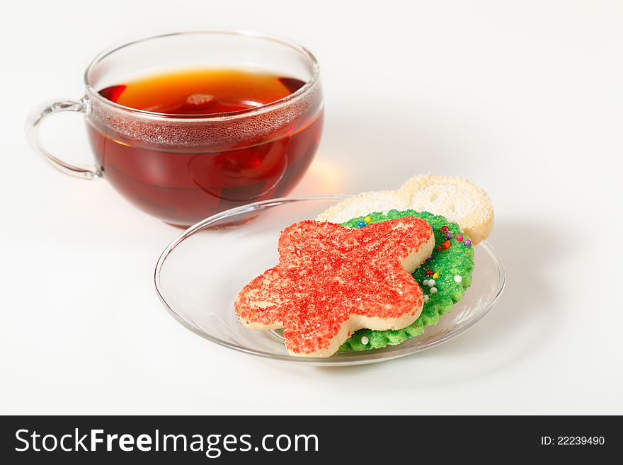 Christmas cookies on a saucer with a glass cup of tea in the background. Focus on the cookies. Christmas cookies on a saucer with a glass cup of tea in the background. Focus on the cookies.