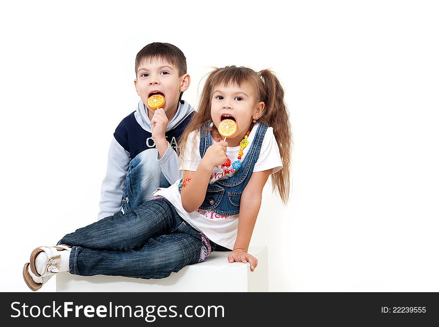 Two cute and happy little kids eating candies isolated on white. Two cute and happy little kids eating candies isolated on white
