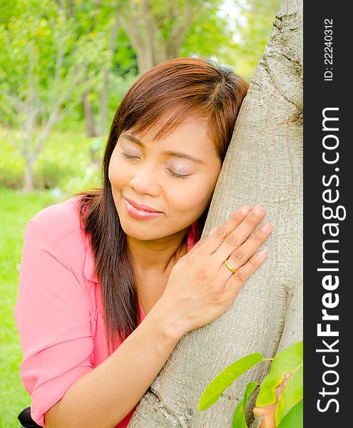 Asian girl close her eyes and listen sound from a tree in park