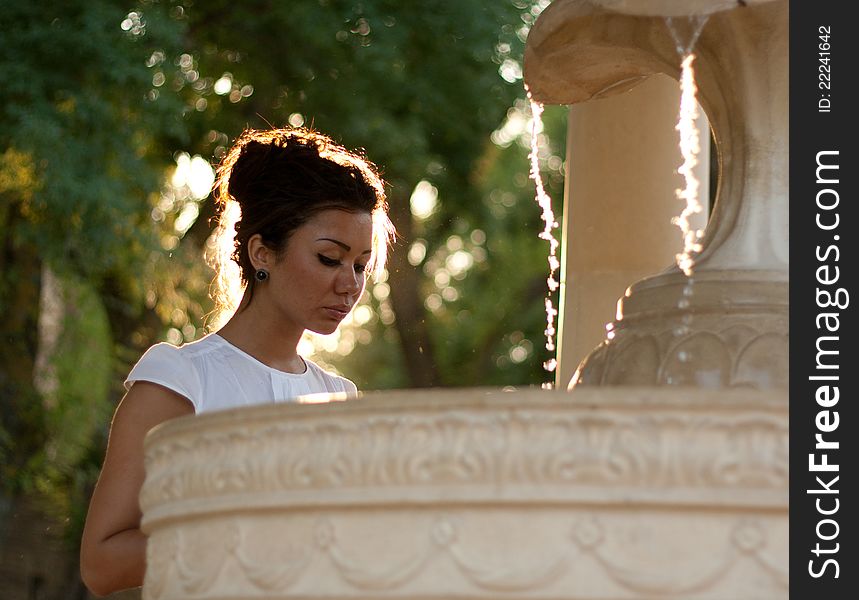 Young brunette woman near the fountain. Young brunette woman near the fountain