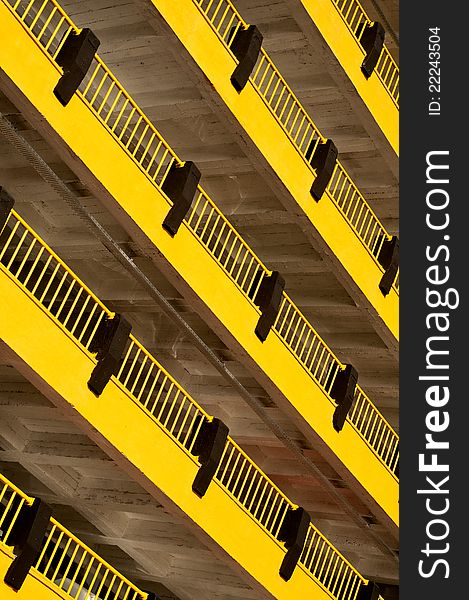 Artistic photo from a multi storey car park building. Yellow color is dominant and black lines are creating a texture. Floor lines are placed diagonally.