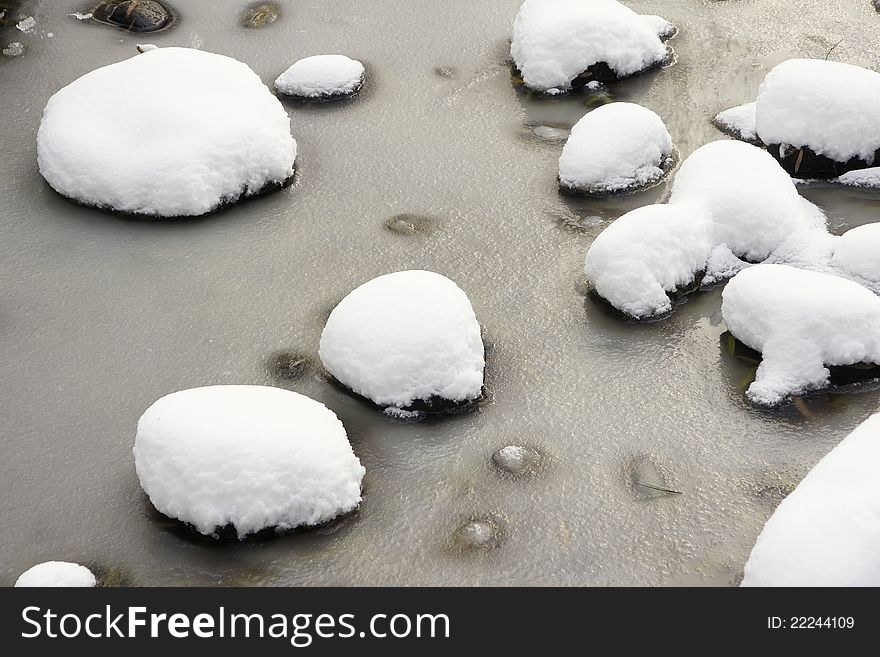 The stones in pond covered with snow. The stones in pond covered with snow