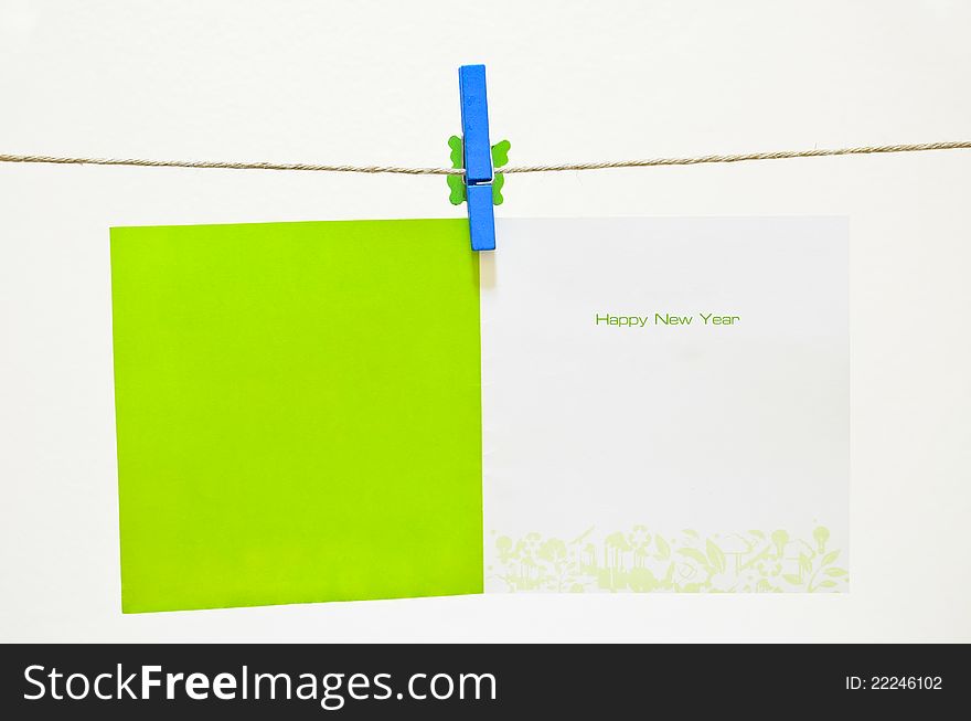 Green clothes-pin holding greeting card on white background