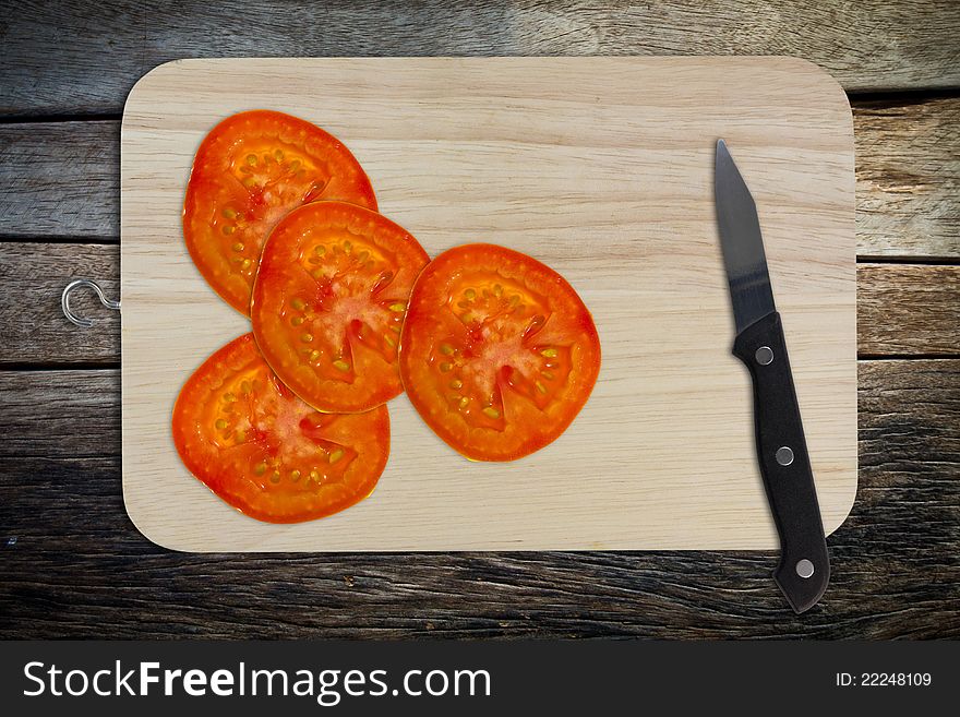 Sliced tomato and knife on chopping board. Sliced tomato and knife on chopping board