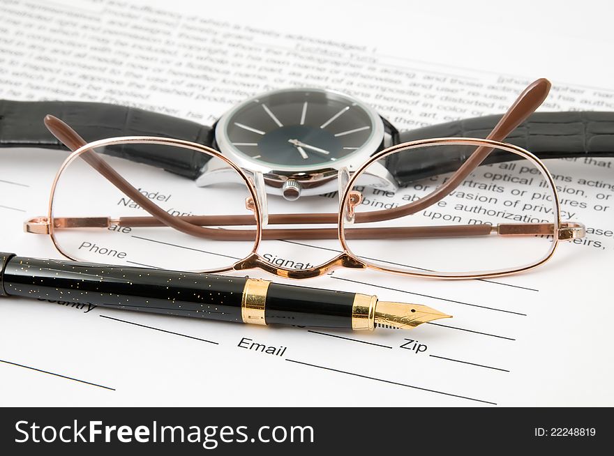 Eyeglasses and pen and wristwatch lay on the document