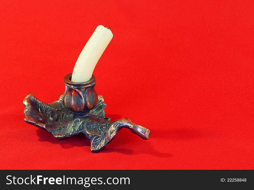 Extinguished the candle in a metal candlestick with a red background. Extinguished the candle in a metal candlestick with a red background