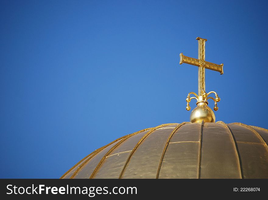 Golden orthodox cross and dome close-up on blue-sky background. Golden orthodox cross and dome close-up on blue-sky background