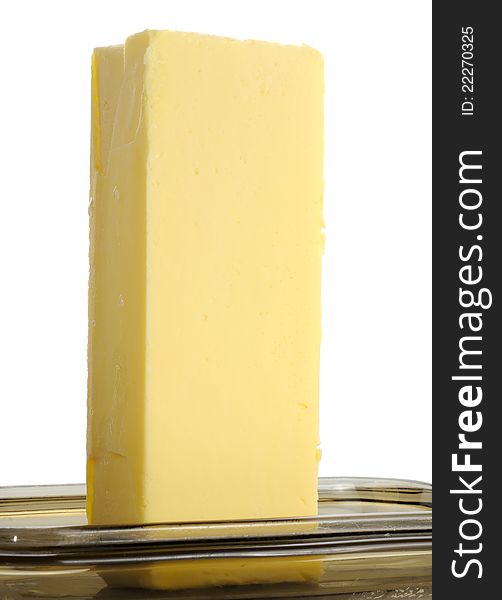A stick of butter on a glass butterdish against a white background. A stick of butter on a glass butterdish against a white background