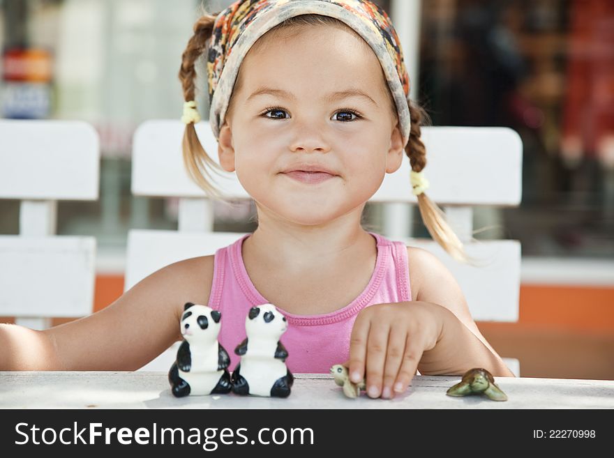 A Girl Playing With Toy Pandas At The Table