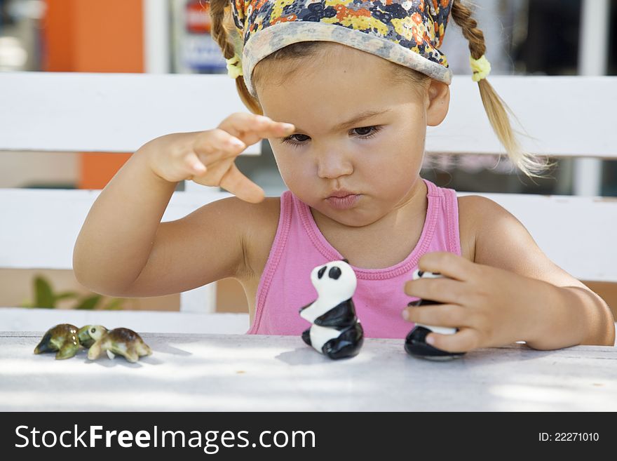 A Girl Playing With Toy Pandas At The Table