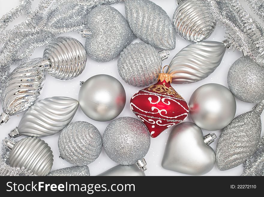 Many silver baubles and one red on white background. Many silver baubles and one red on white background