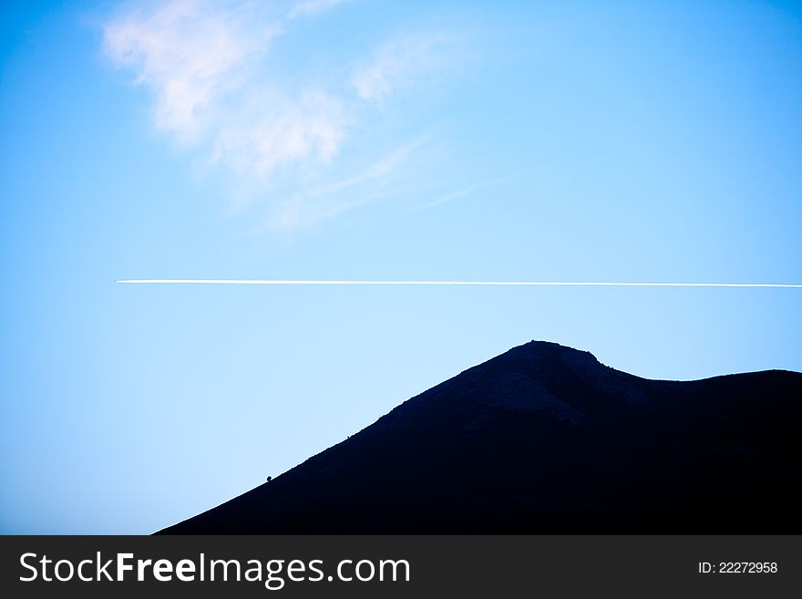 A silhouette of a hill top with blue sky during sunset. A silhouette of a hill top with blue sky during sunset.