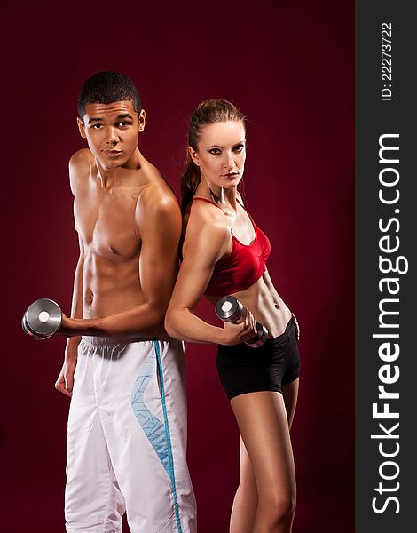 Strong young man and woman with dumbbells