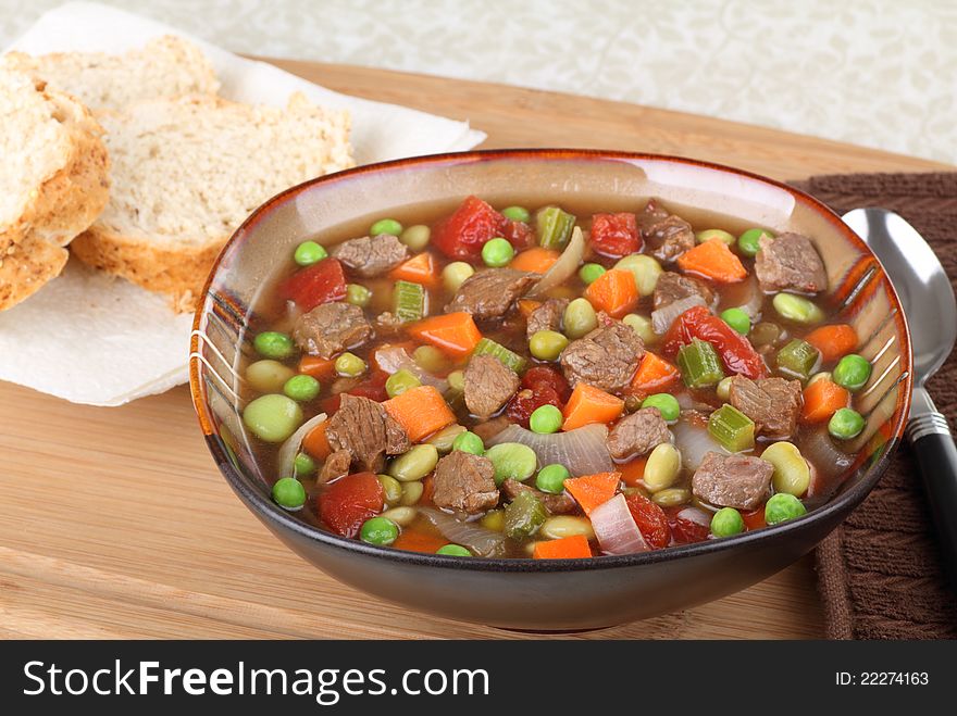 Vegetable beef soup in a bowl with bread on the side. Vegetable beef soup in a bowl with bread on the side