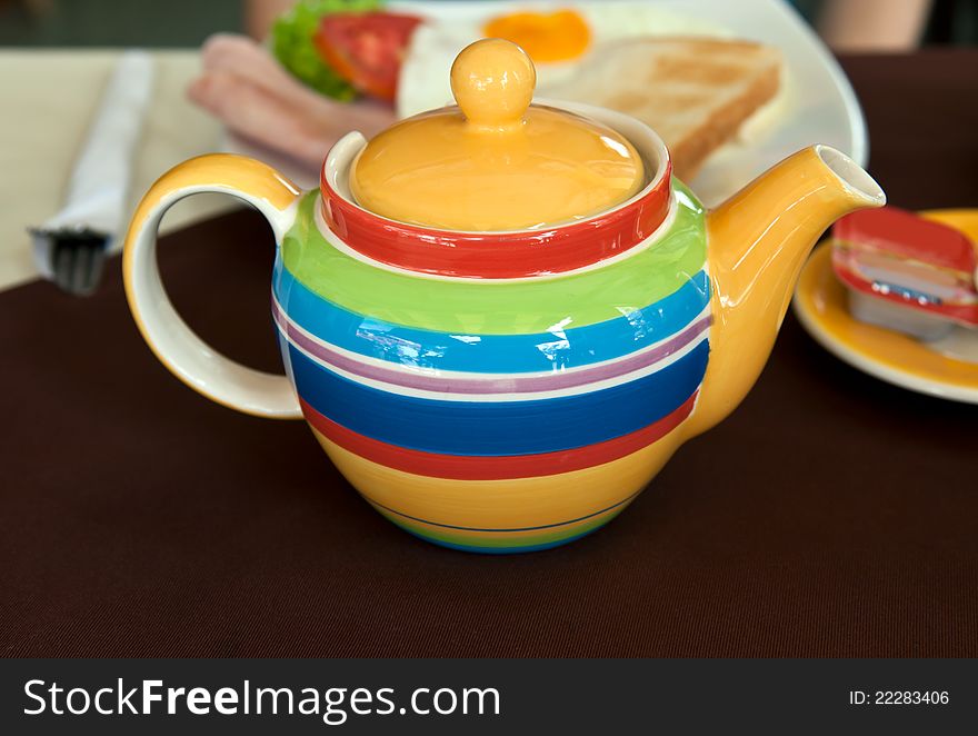 Colored striped teapot on the table with breakfast