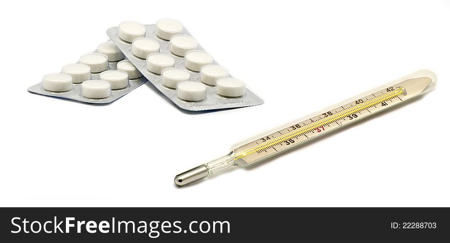 Pills and a thermometer on white background. Pills and a thermometer on white background