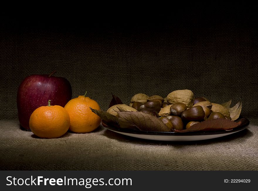 Red apple with mandarins and nuts over jute background. Red apple with mandarins and nuts over jute background