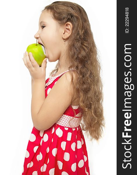 Little girl in pink clothes eats green apple