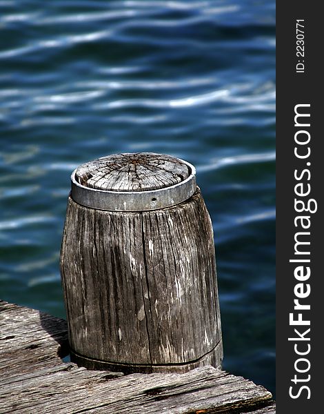 Wooden Pole Marking A Footpath Next To The Blue Ocean Surface