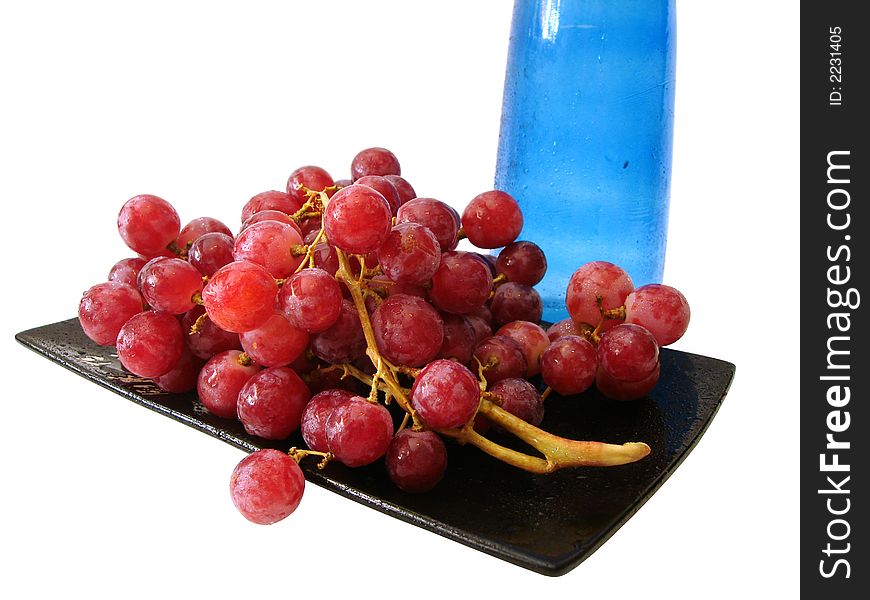 Dish with grapes and blue bottle over white background. Dish with grapes and blue bottle over white background