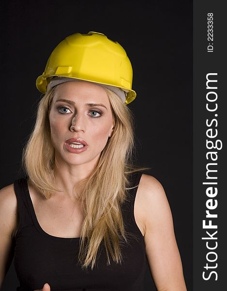 Sexy blond female construction worker with hard hat and tool pouch on black background. Sexy blond female construction worker with hard hat and tool pouch on black background