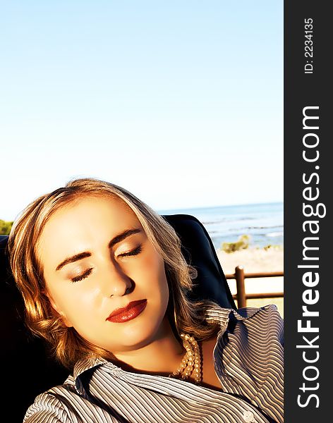 Portrait of a blonde woman sitting in the chair on holiday by the ocean.