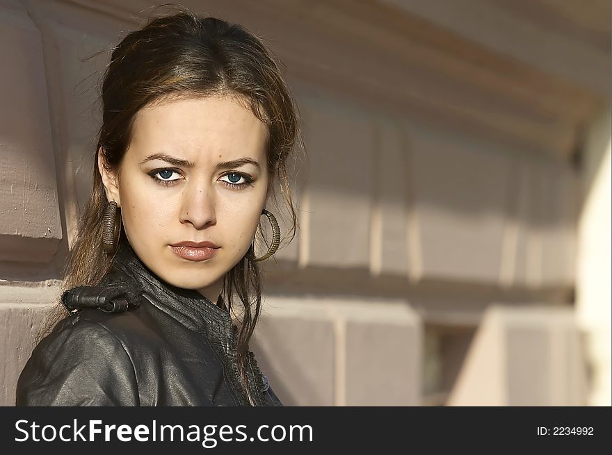 Attractive young woman posing leaning against a wall